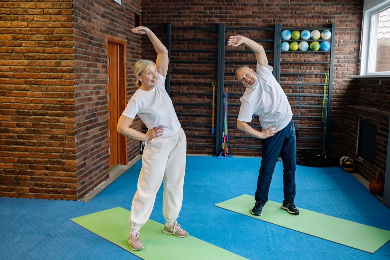Elderly couple stretching on yoga mats in a home gym, embracing a healthy lifestyle.
